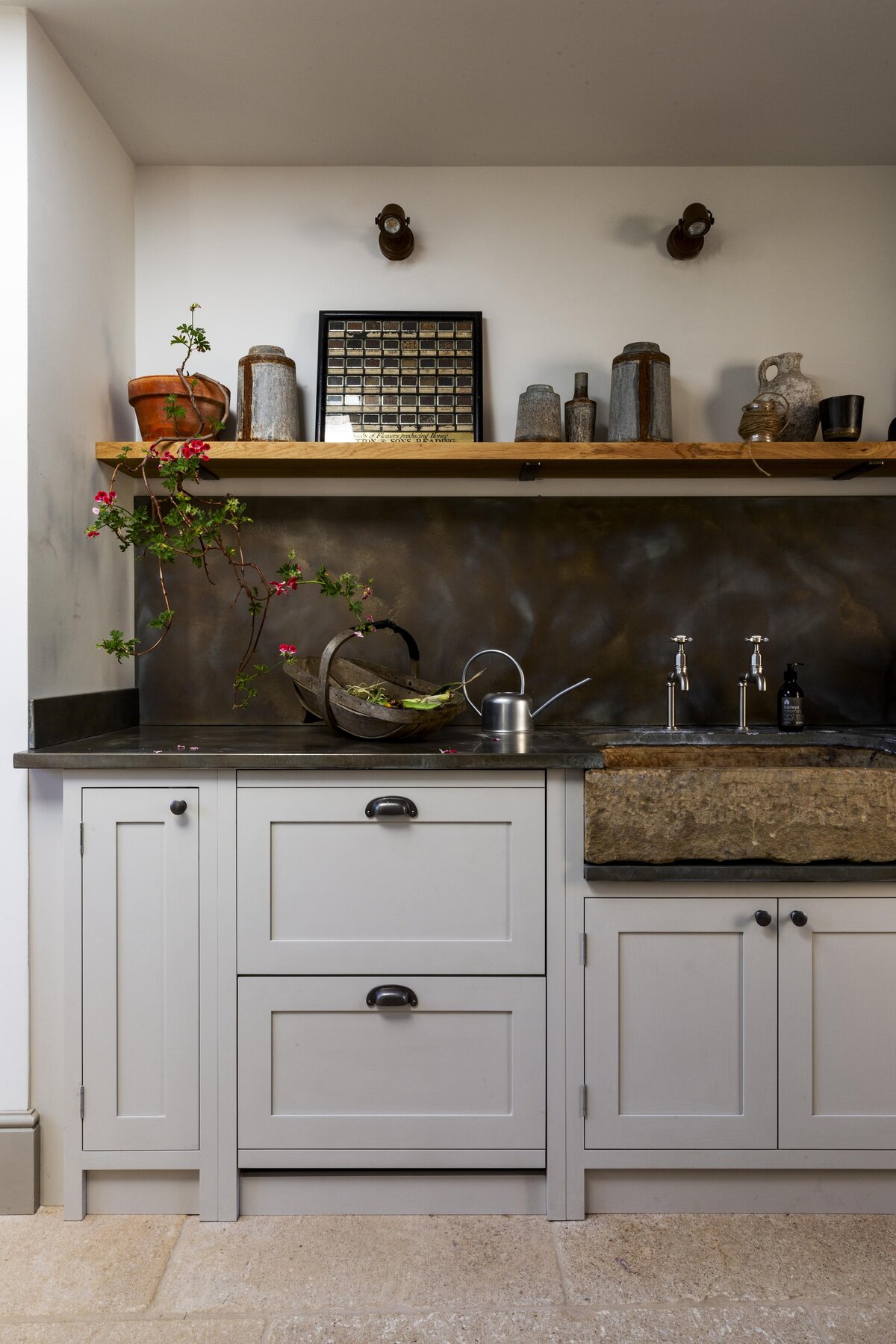 Grey cabinets with dark metal splashback and flower vase on the counter