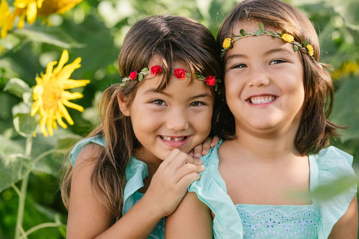 sisters snuggle in a sunflower field