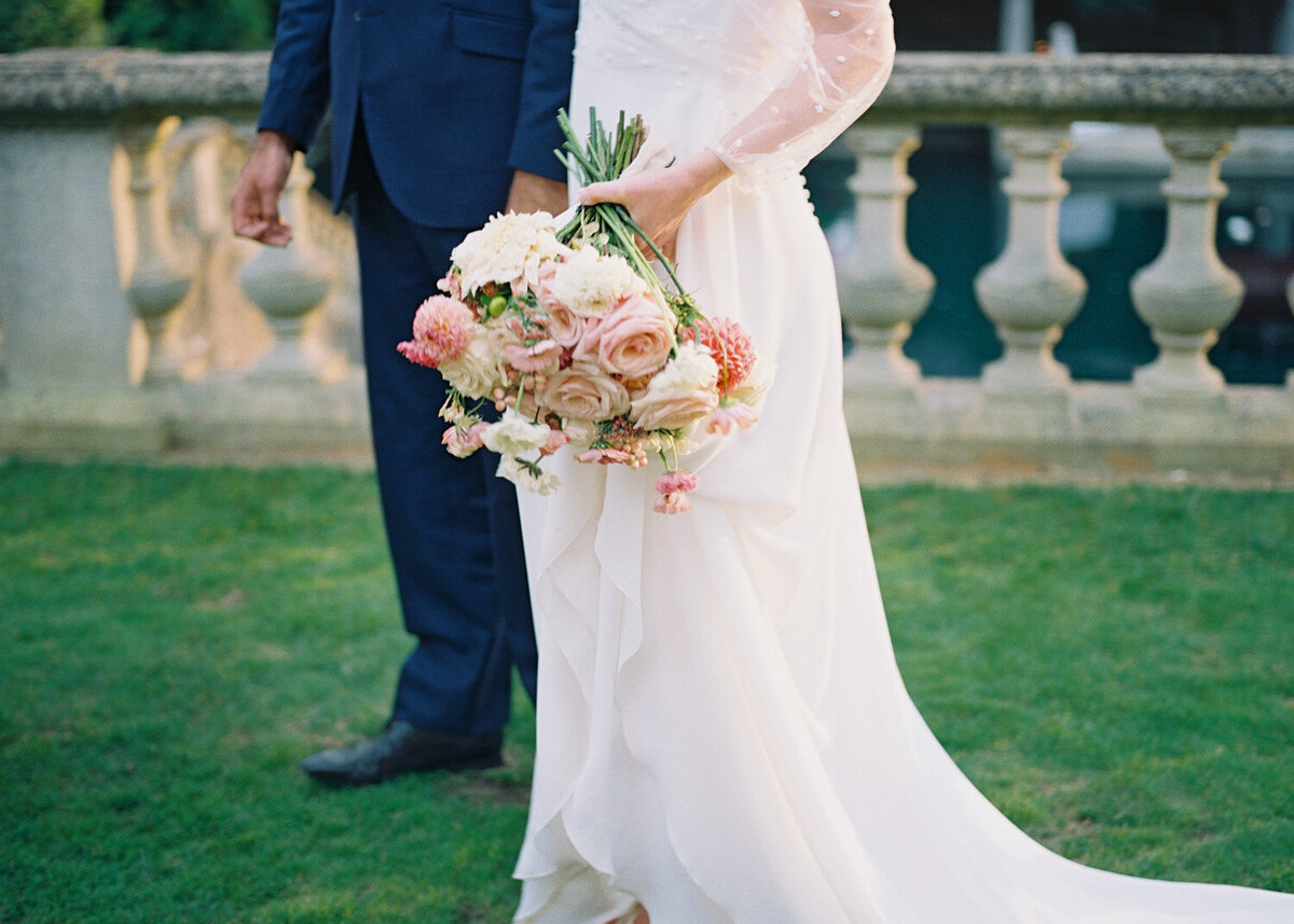 bride holding large pink blush and white flower bouquet during couple golden hour session