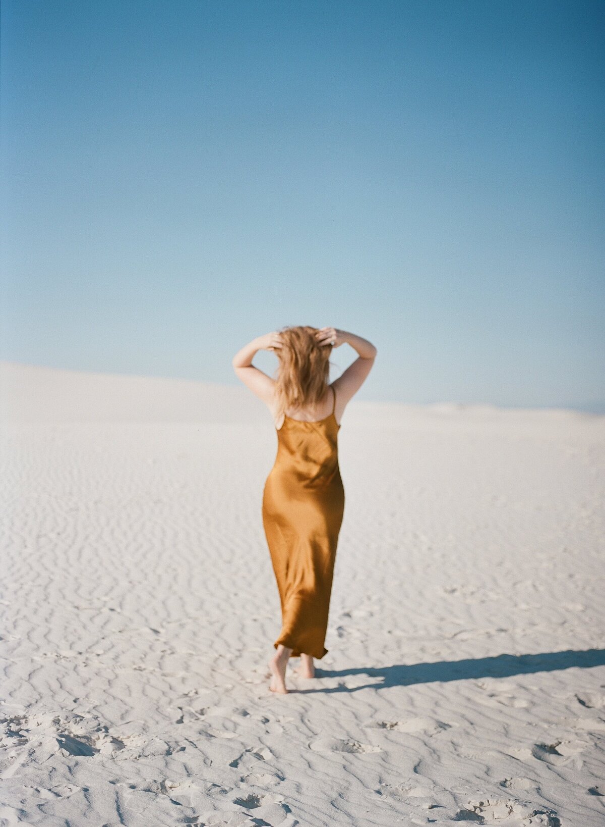 Woman with auburn hair and dress in white sands