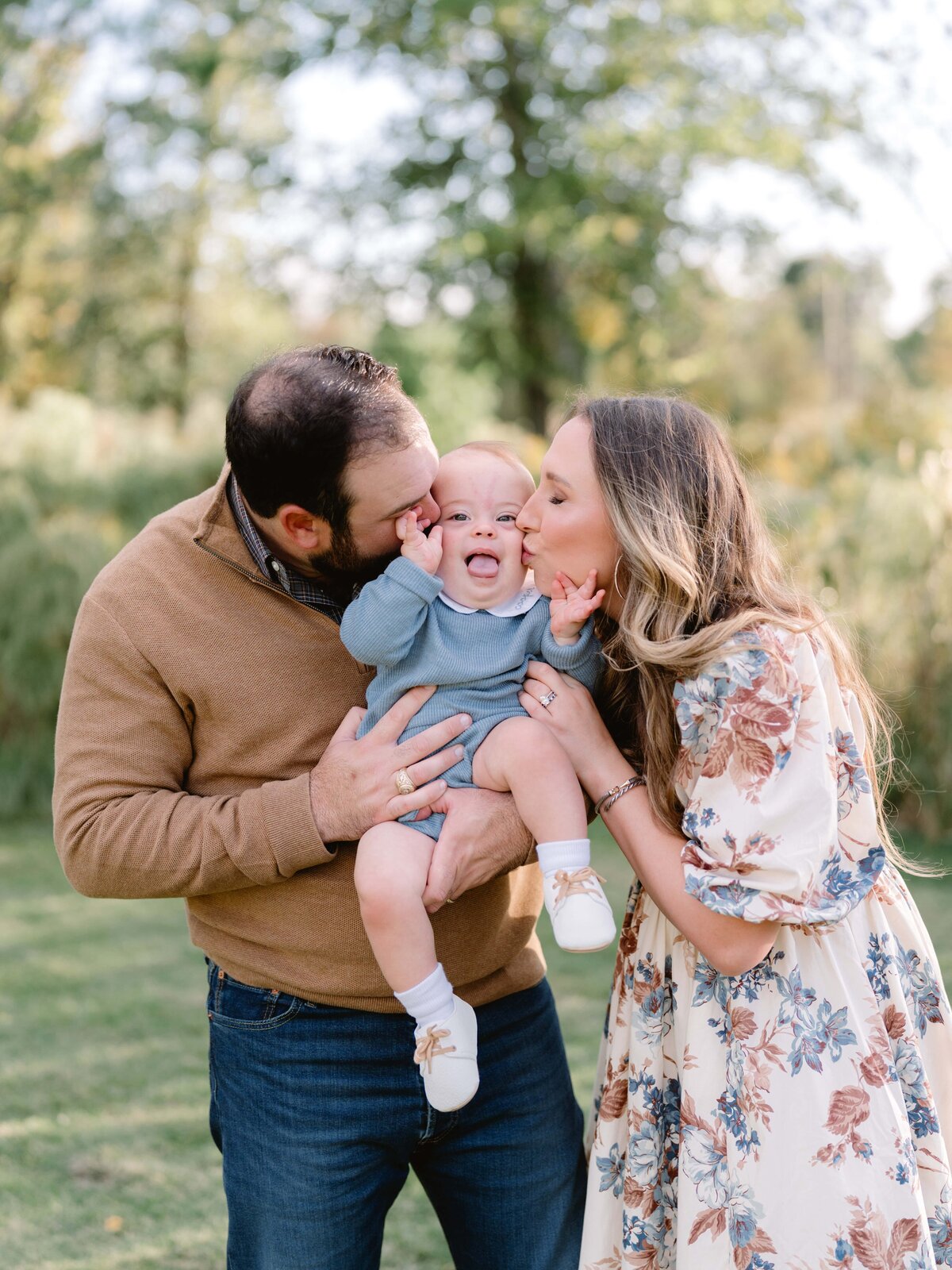 Mother and father kissing each side of baby's cheeks