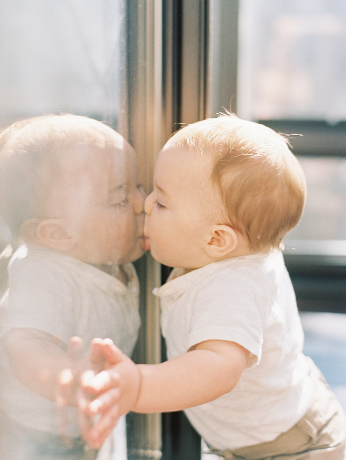 little boy kissing window