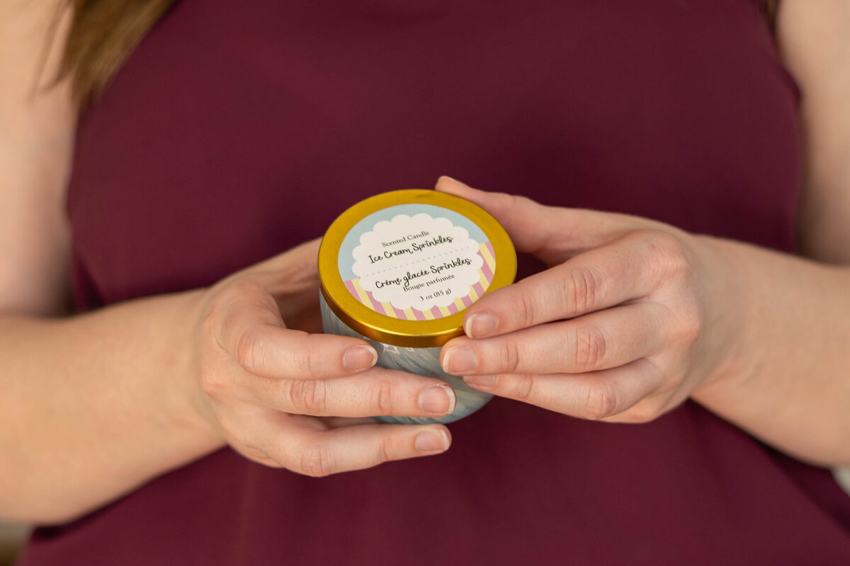 Woman holding a small jar of lemon-scented cream, with clear view of the product label.