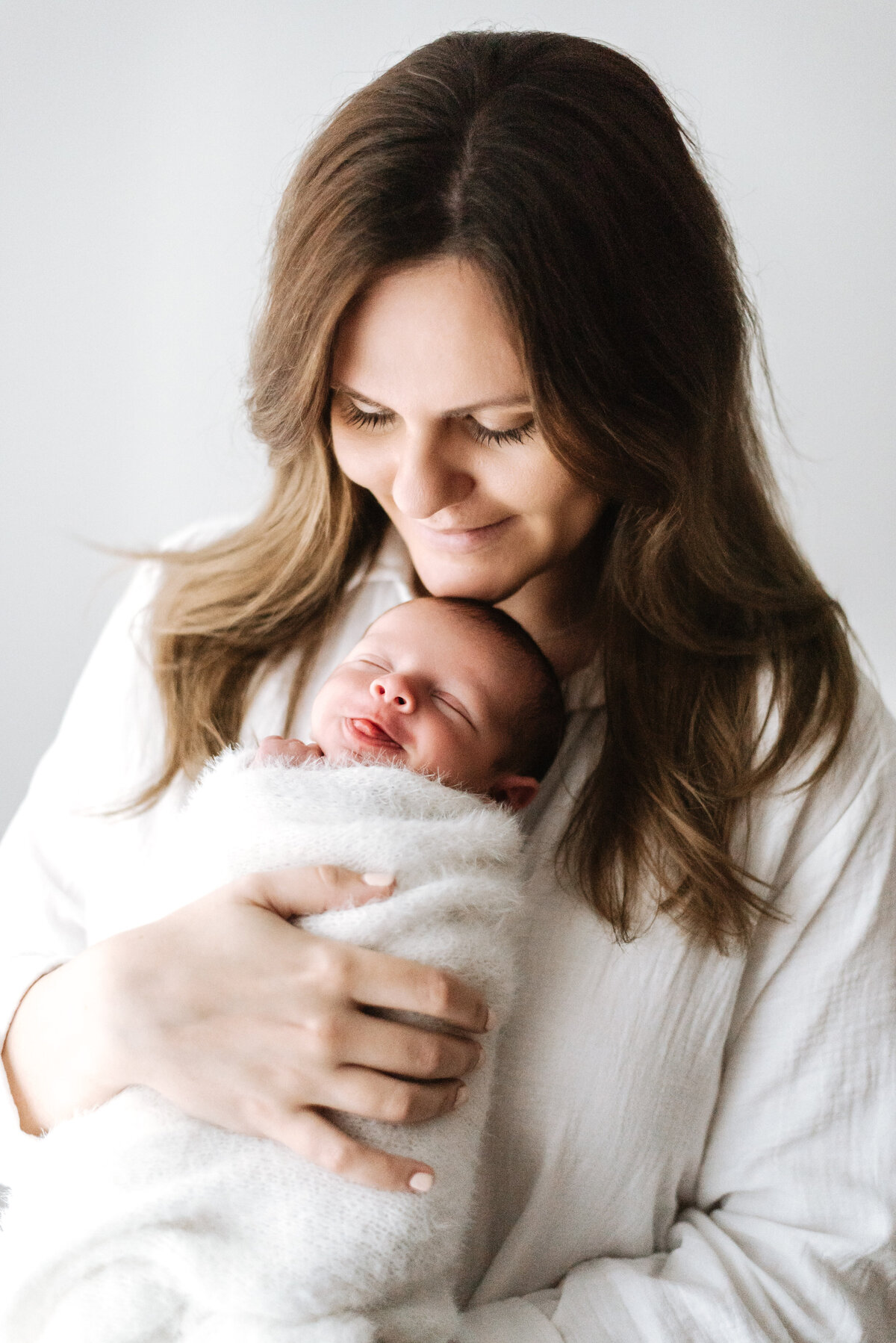 Mother smiling holding her baby at newborn photoshoot in Billingshurst