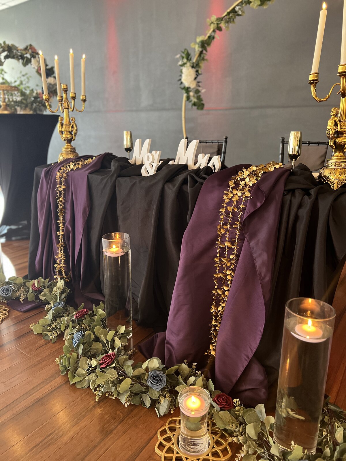 Dark and moody wedding reception headtable at our Clearwater, Florida event venue, The District - Inclusive decor package featuring dramatic candleabras and floating candles for an enchanting ambiance