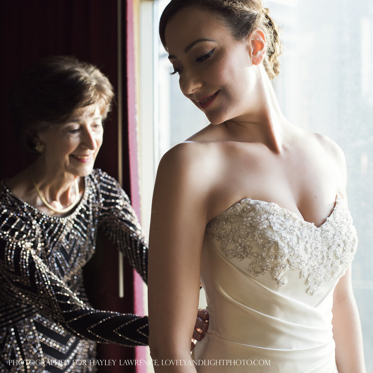 charlotte wedding photographer jamie lucido captures a beautiful moment at the hotel as the bride puts on her dress and her mother zips it from behind