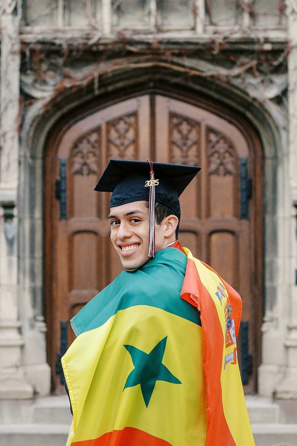 Graduate with Spain and Senegal flags draped over his shoulders