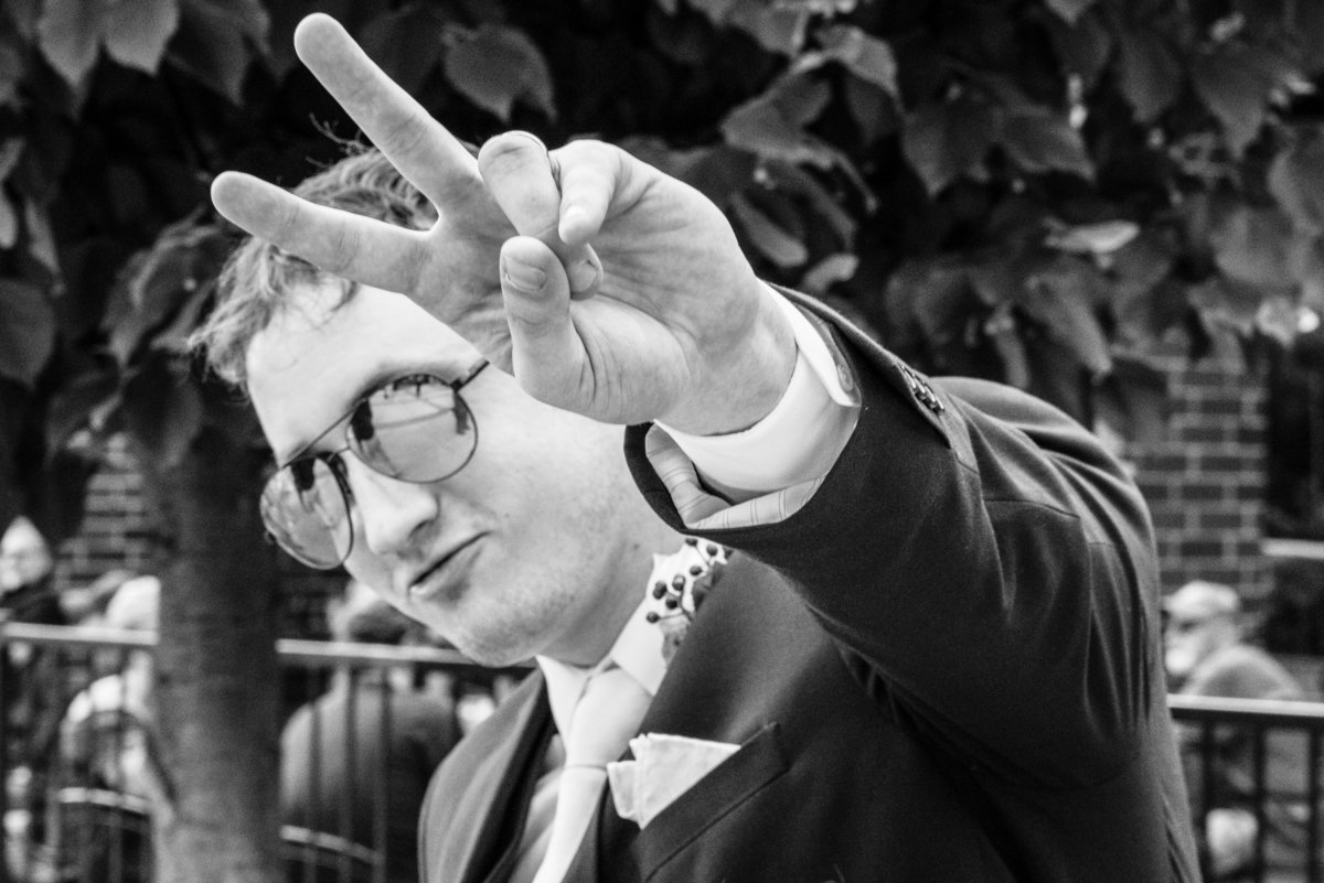 Groom flashes peace sign while wearing sunglasses.