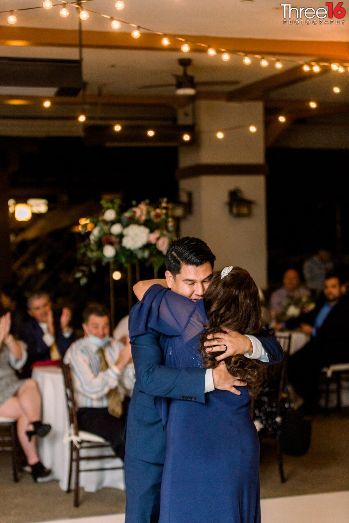 Groom hugs his mother after their dance together
