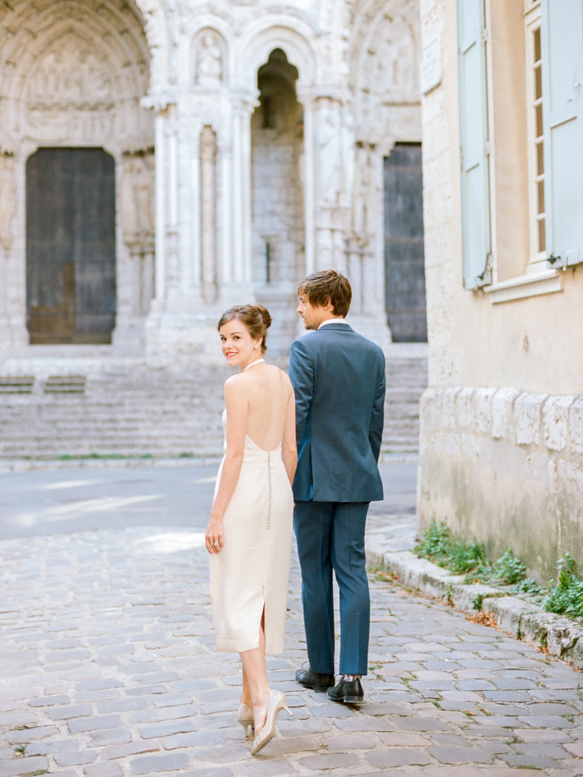 couple walking down cobblestone street in france