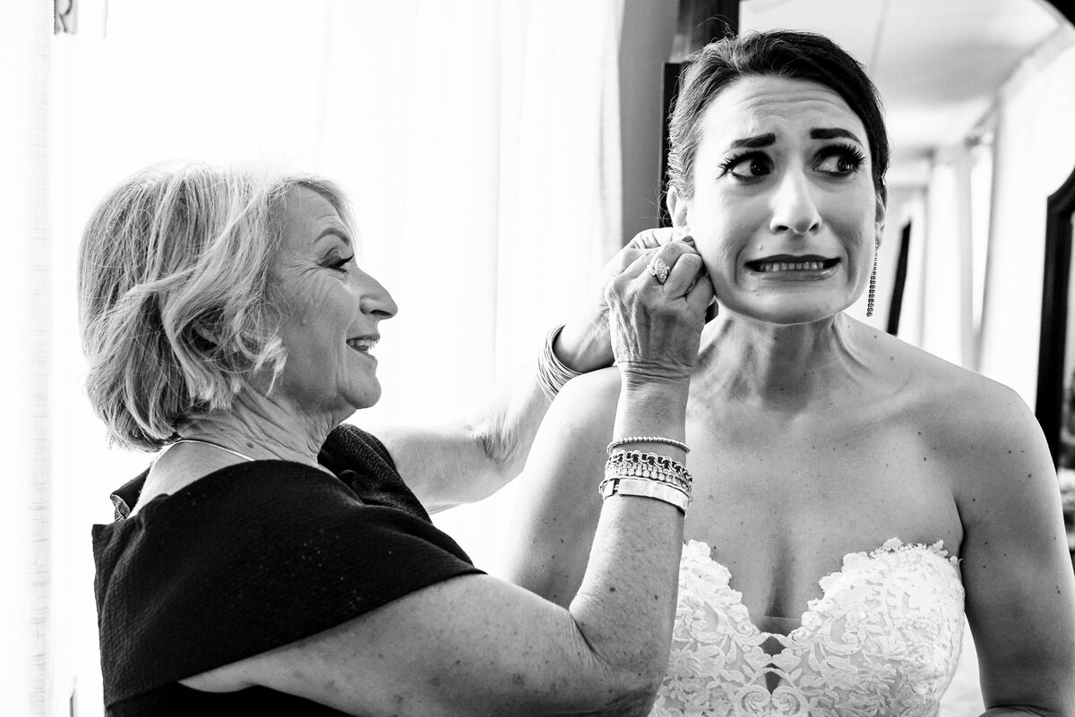 Black-and-white-candid-image-of-a-bride-nervously-allowing-her-mother-to-put-in-her-earrings-in-the-bridal-suite-of-Childress-Vineyards