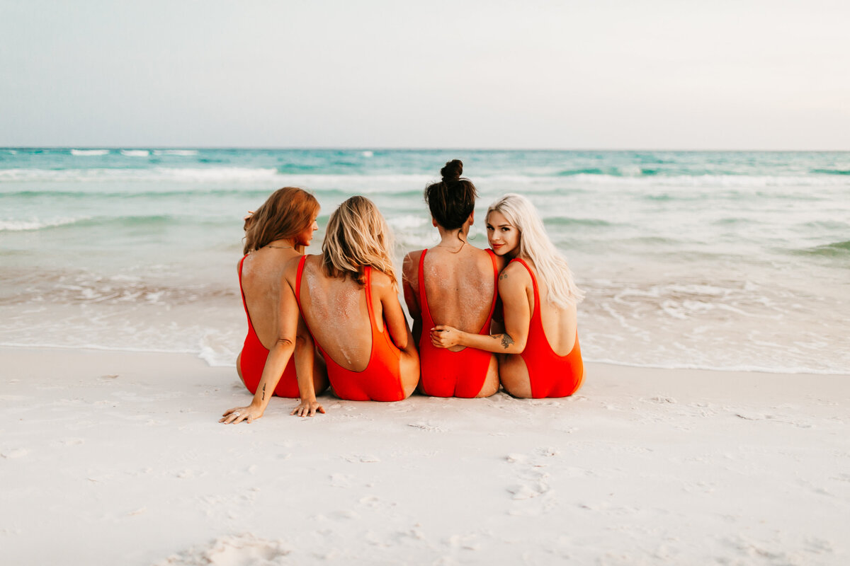 girls sitting on the beach in red swimsuits