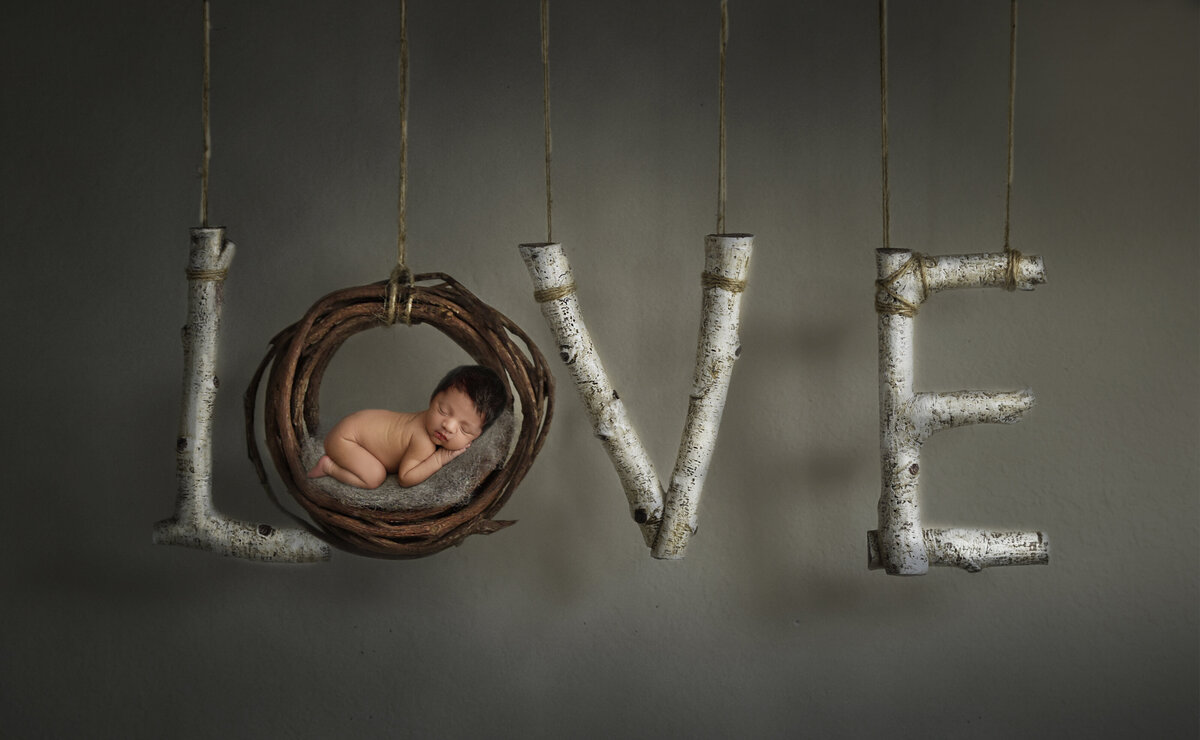 baby boy sleeping on a wooden love sign