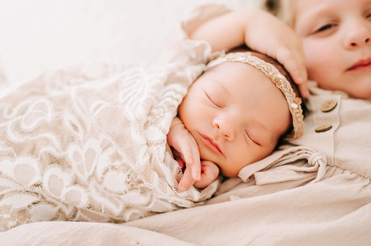 sleeping newborn baby girl on sisters chest captured in Springfield MO newborn photography studio