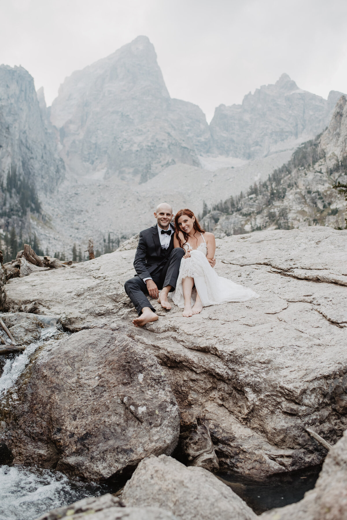 Jackson Hole Photographers capture couple sitting barefoot on boulder