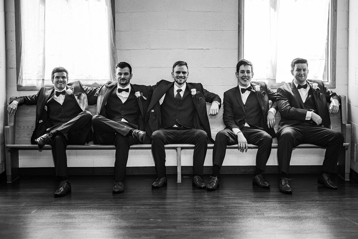 black and white groom with groomsmen sitting on bench