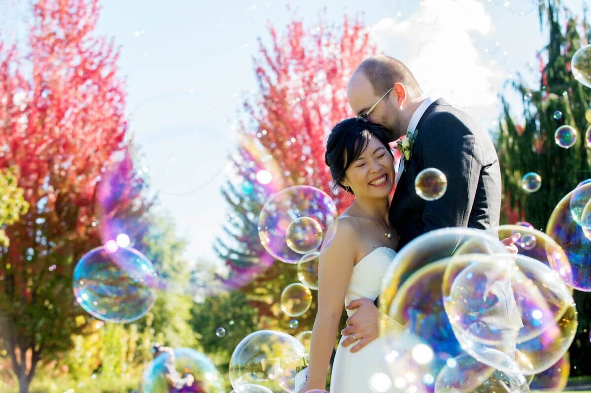 colorful photo of bride and groom hugging with rainbow bubbles surrounding them
