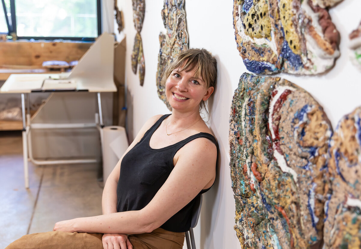 A ceramic artist poses in front of her sculptures during her peresonal branding photoshoot.