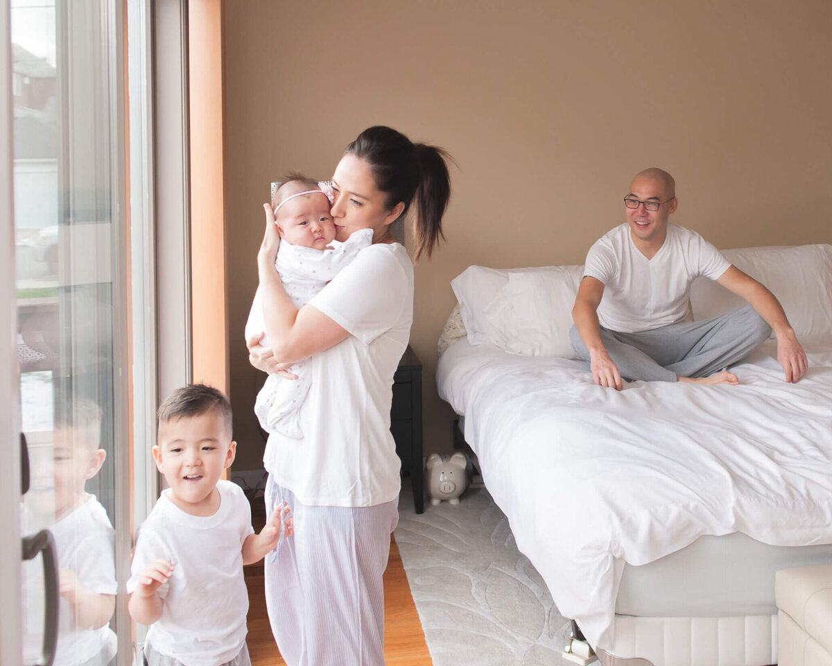 family at home with their new baby all in white tee shirts and grey sweats