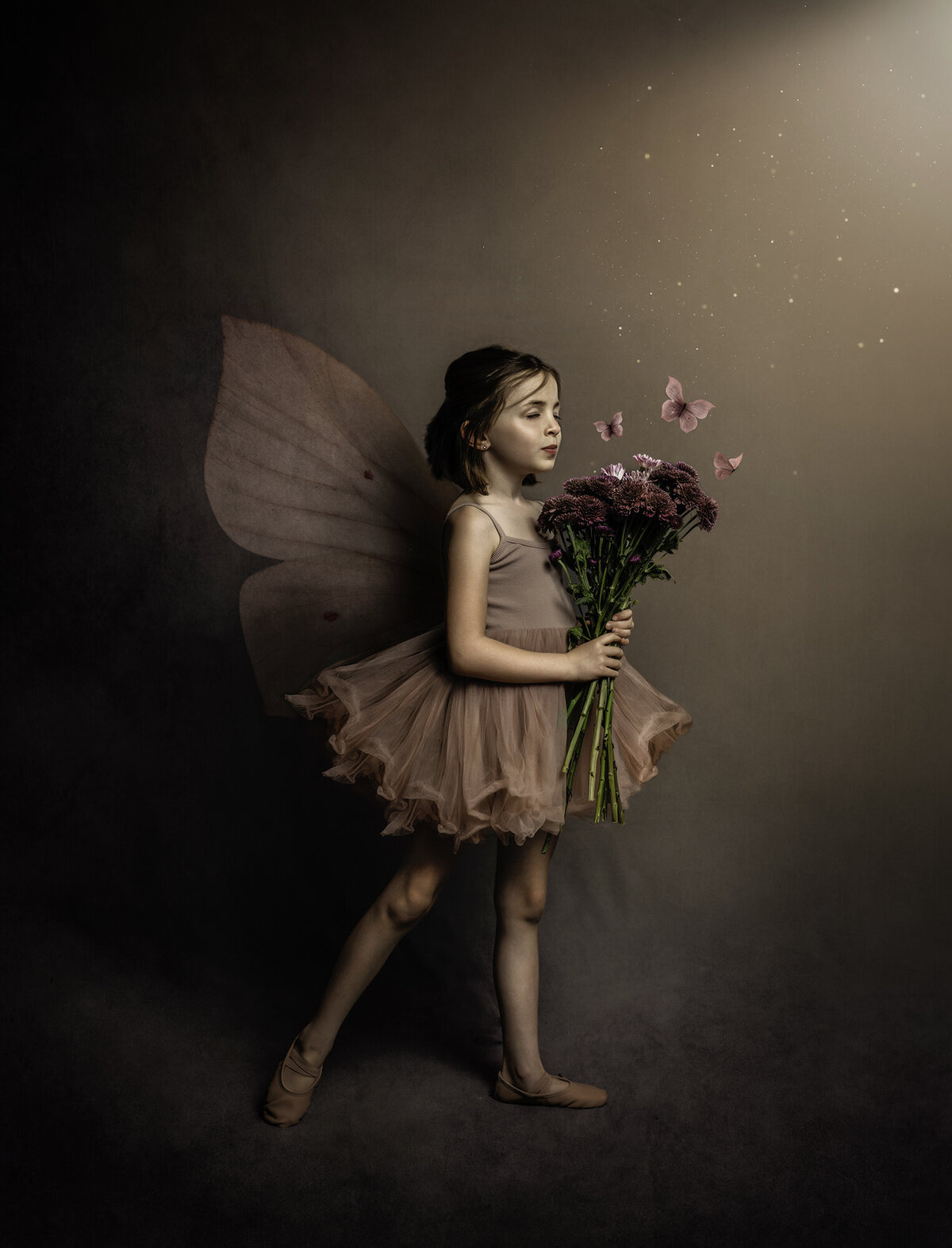 A little girl dressed as a fairy and holding flowers while butterflies fly around