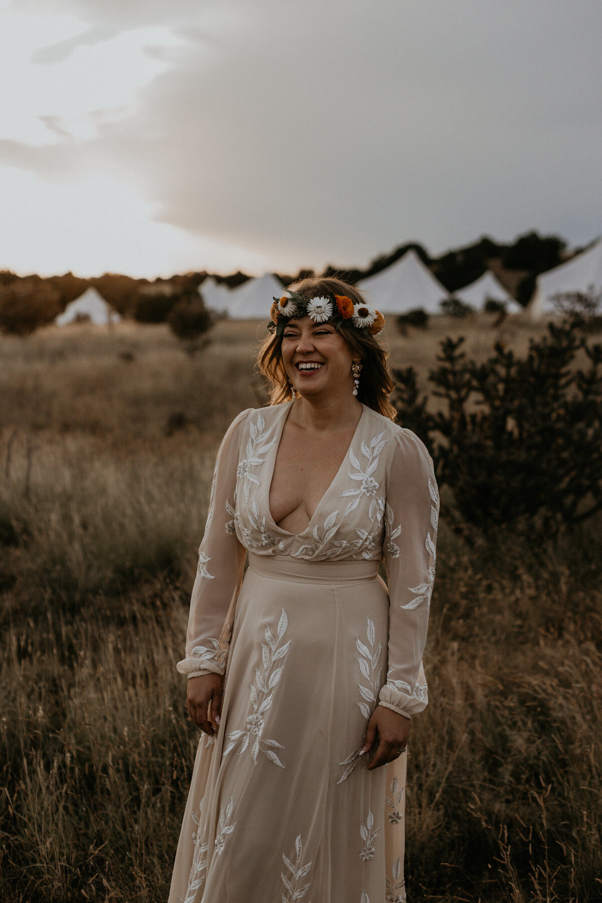 bride standing in the desert in front of glamping tents