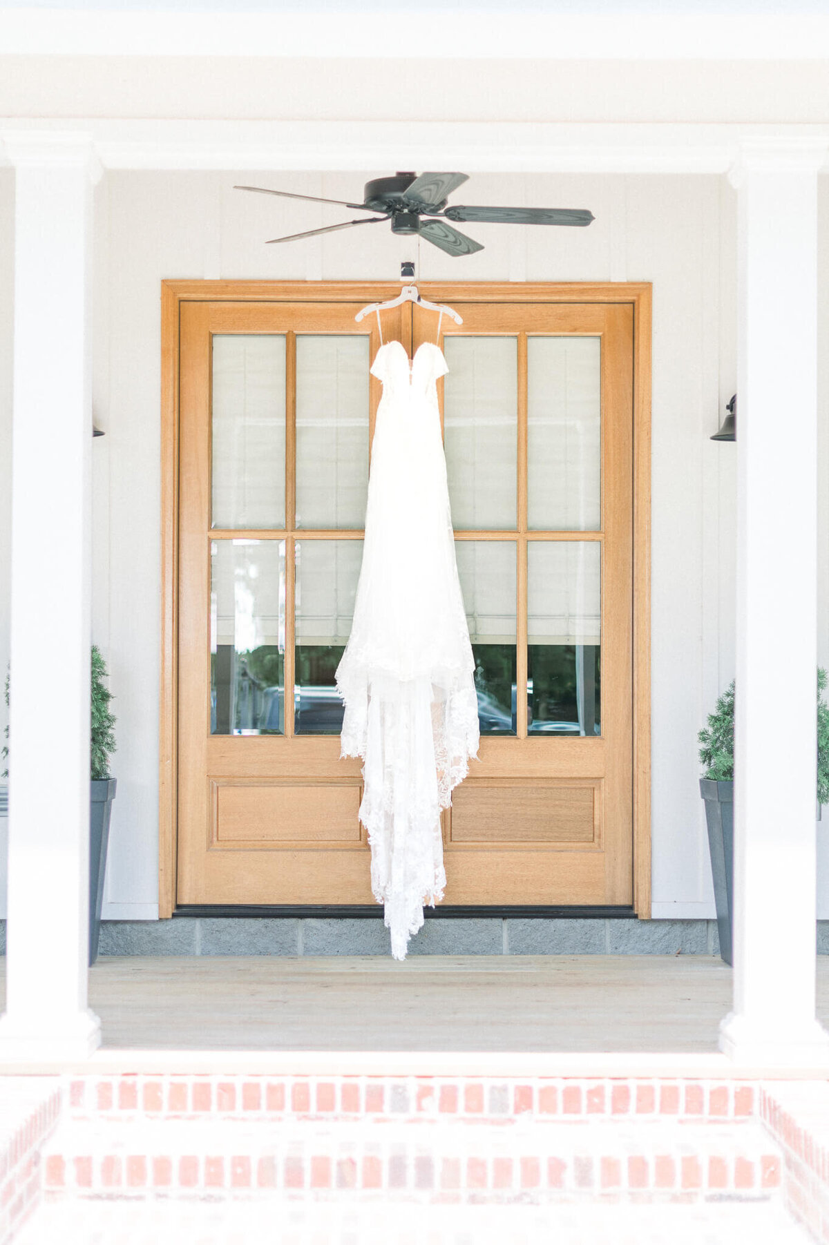 photograph of hanging wedding dress in front of a wooden and glass door at the silos in bono arkansas