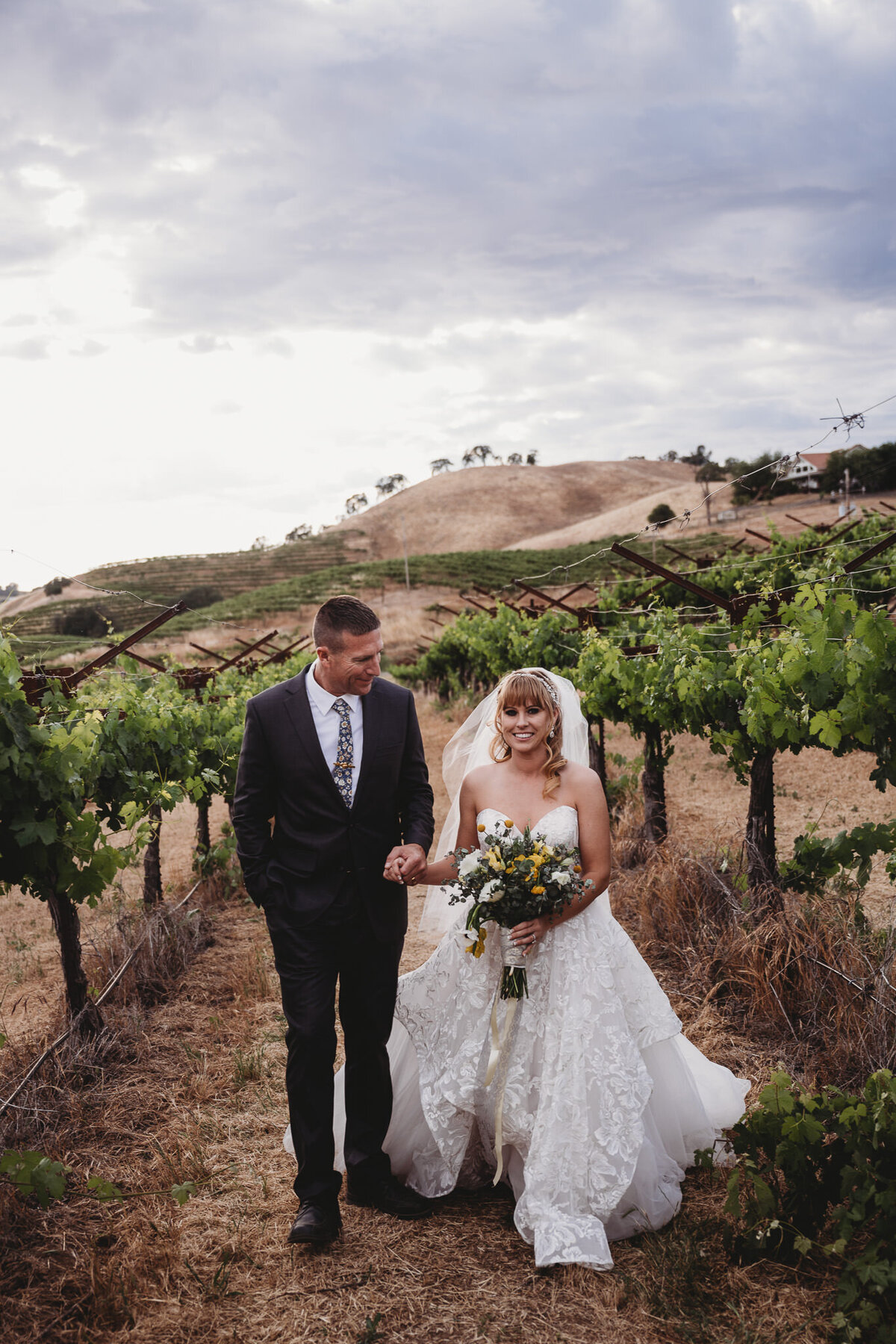 Bride and groom walking hand in hand in a vineyard in California