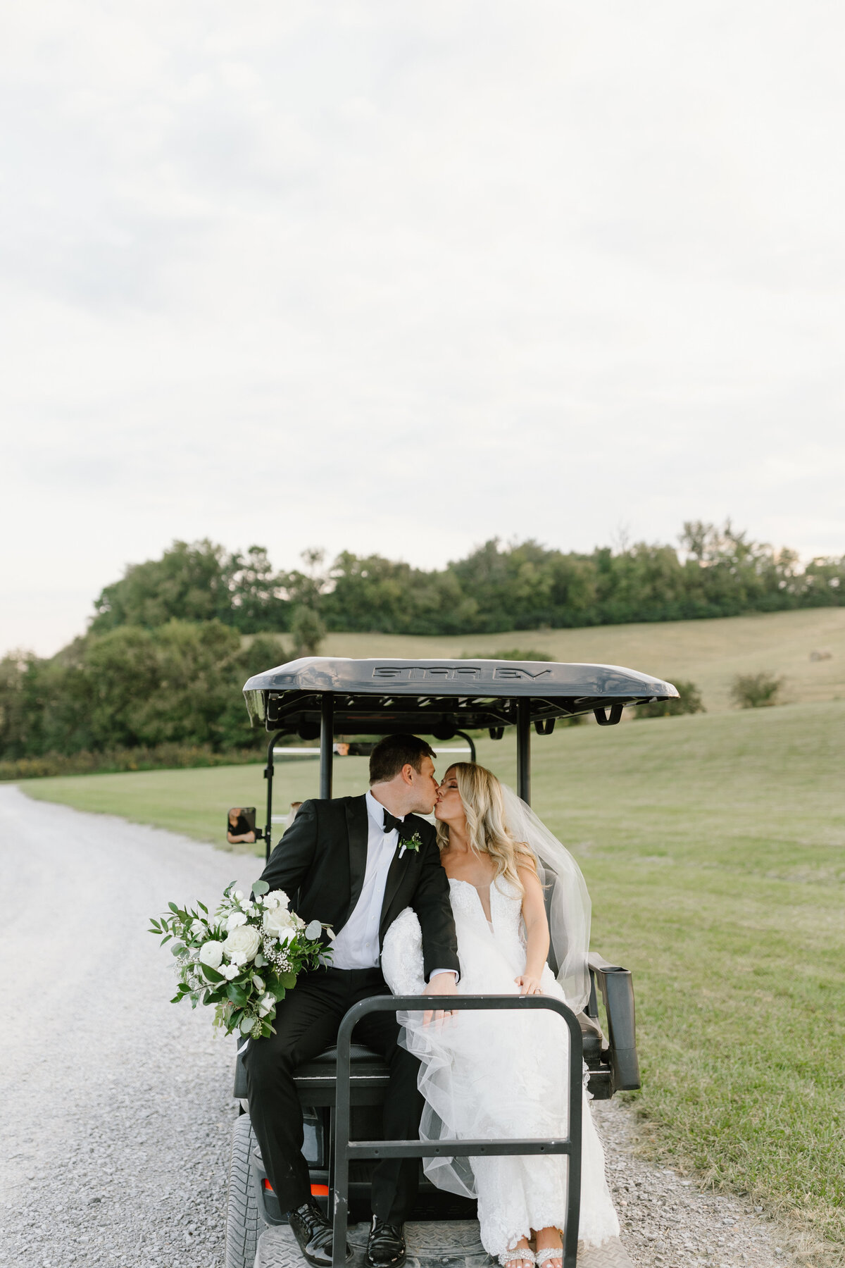 Newlyweds steal a kiss while driving away on golf cart