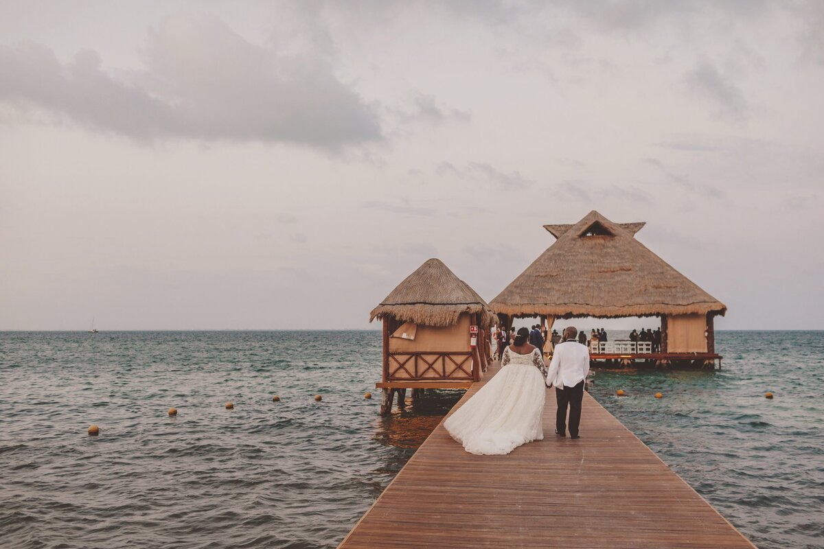 Bride and groom walking away on dock at wedding in Cancun
