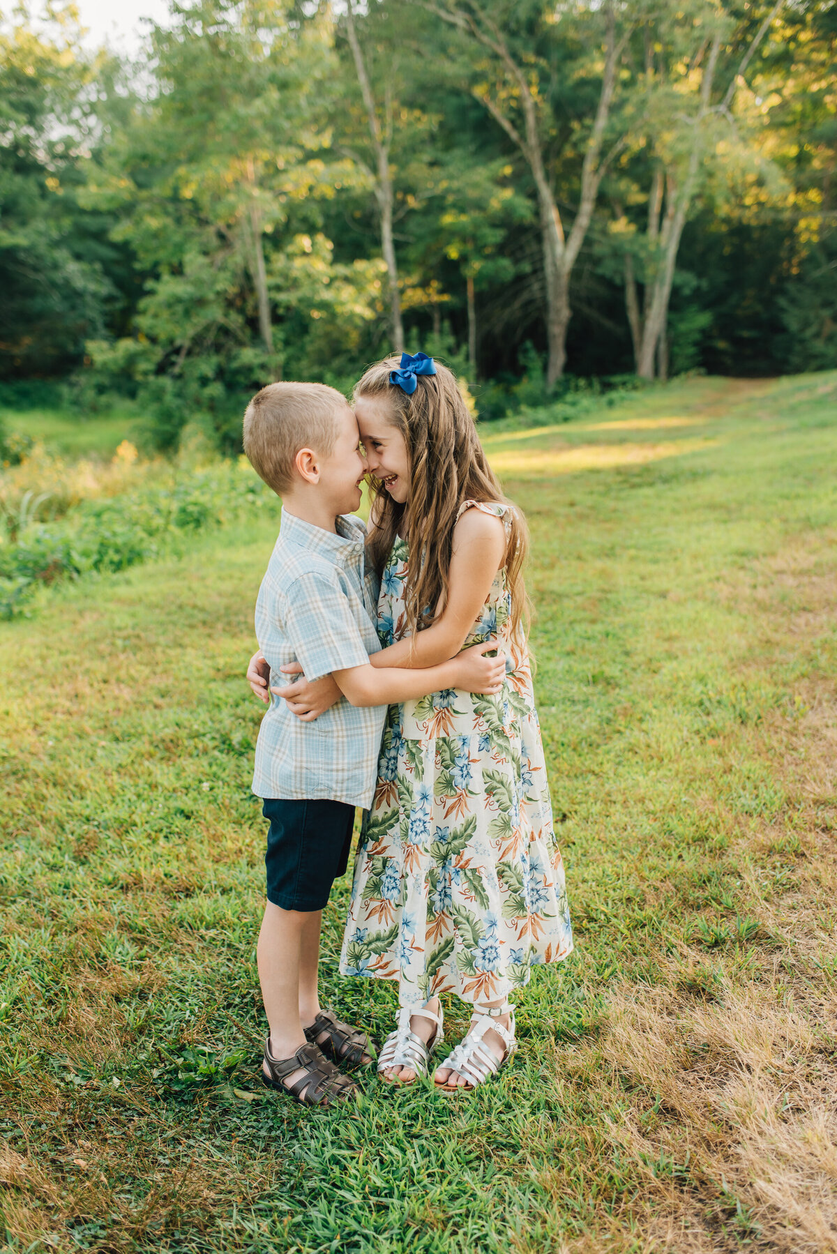Brother and sister touching foreheads in a field