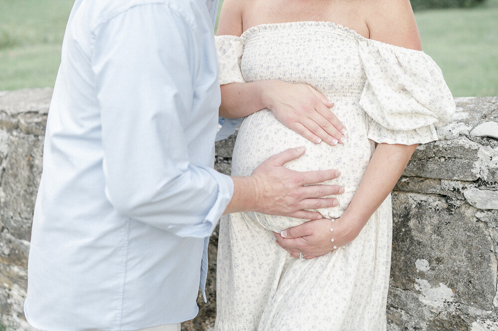 Hands rest on a pregnant woman's stomach