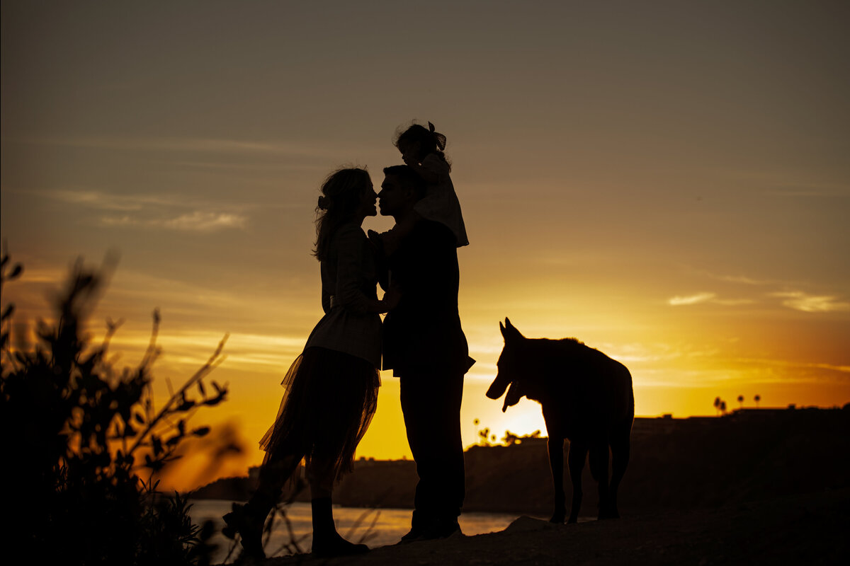 Silhouette picture of mom, dad, daughter and shepherd at palos verdes beach in Los Angeles California during sunset golden hour.