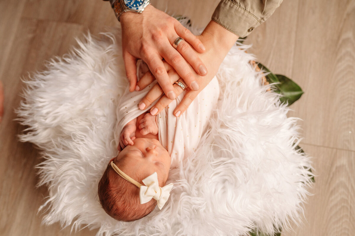 photo of newborn with parent's hands on her