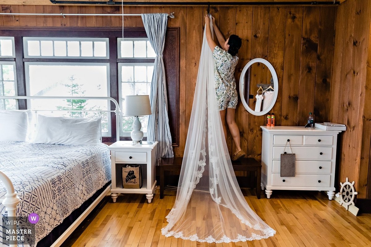 Linekin Bay Resort Wedding the bridesmaid hangs the cathedral length veil in the cabin in Boothbay Harbor Maine