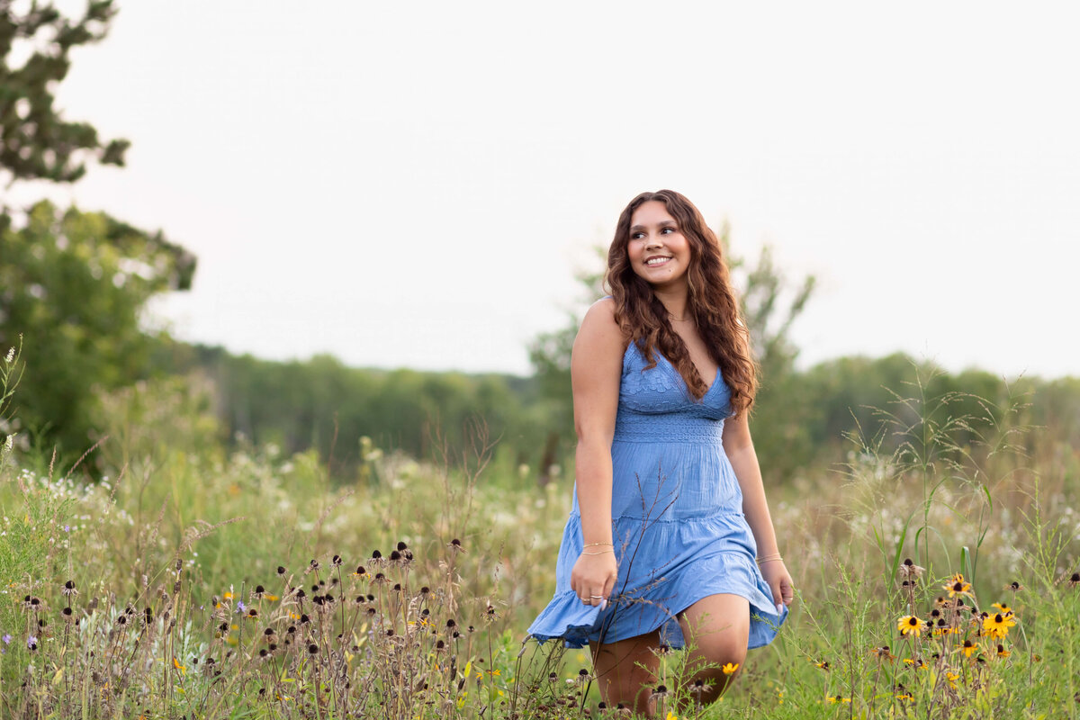 girl in blue dress walking through wildflower field