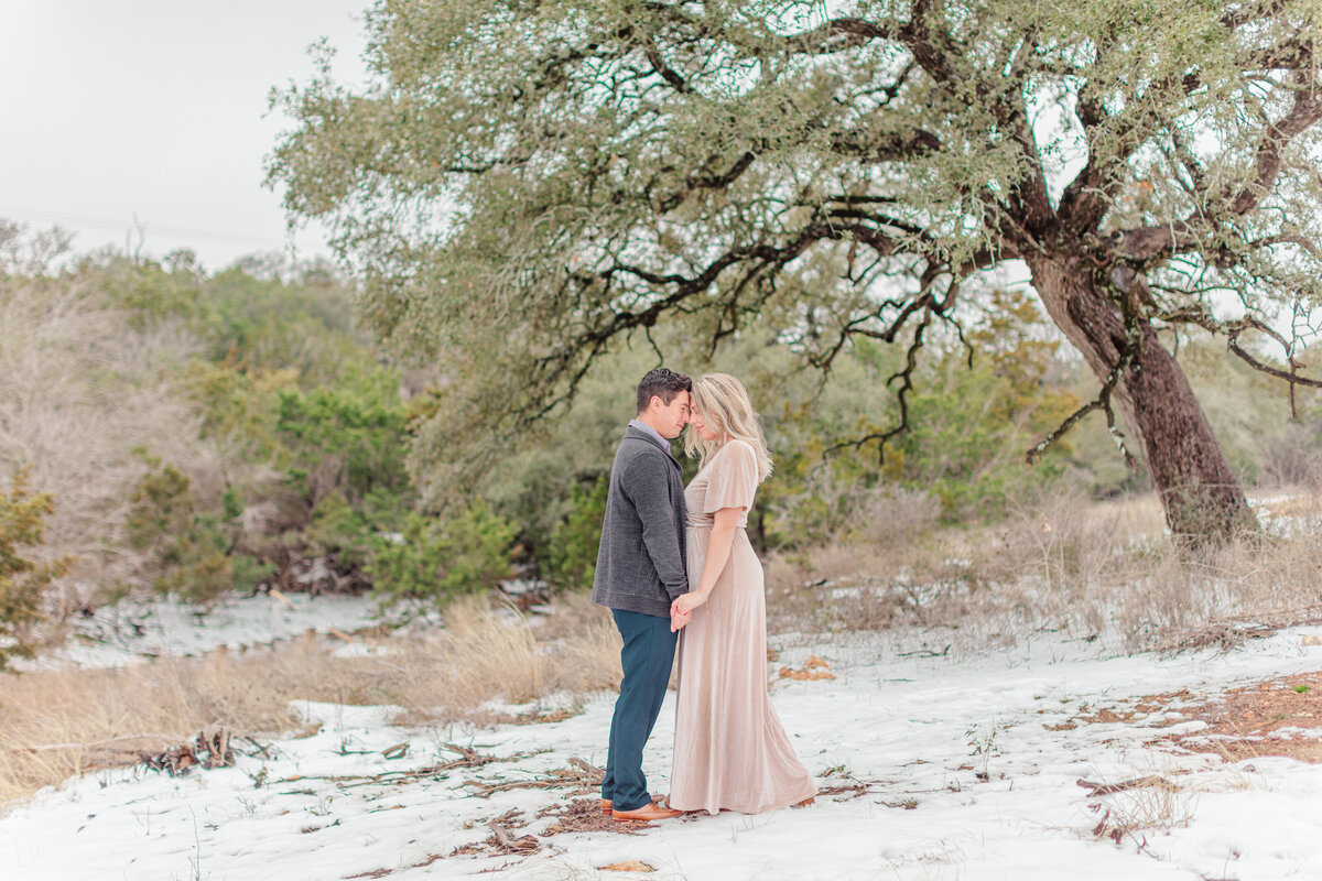engagement session in snow hilltop with winter trees and velvet dress touching foreheads by Firefly Photography