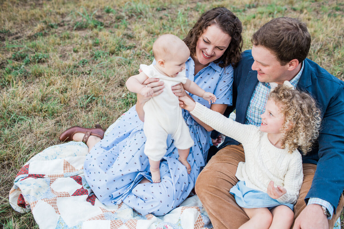 family sitting on a blanket laughing at fall photo session in Chattanooga