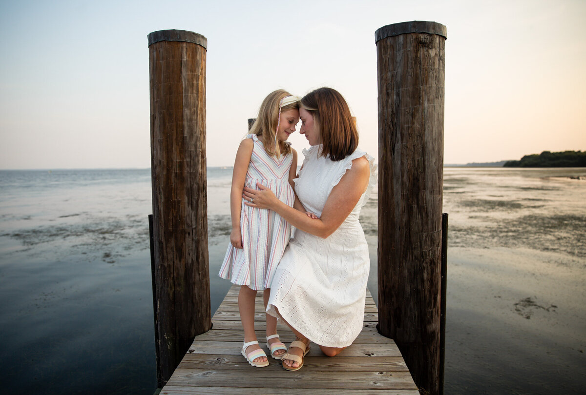 A mother embraces her daughter forehead-to-forehead on a fishing pier during their lifestyle family session in Harford County, Maryland