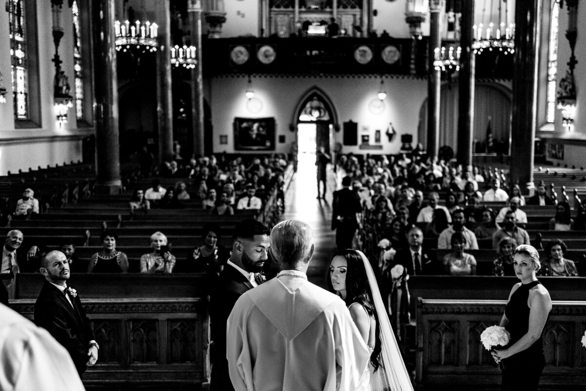 One of the top wedding photos of 2021. Taken by Adore Wedding Photography- Toledo, Ohio Wedding Photographers. This photo is of the bride and groom in the historic church of st. pats in Toledo Ohio