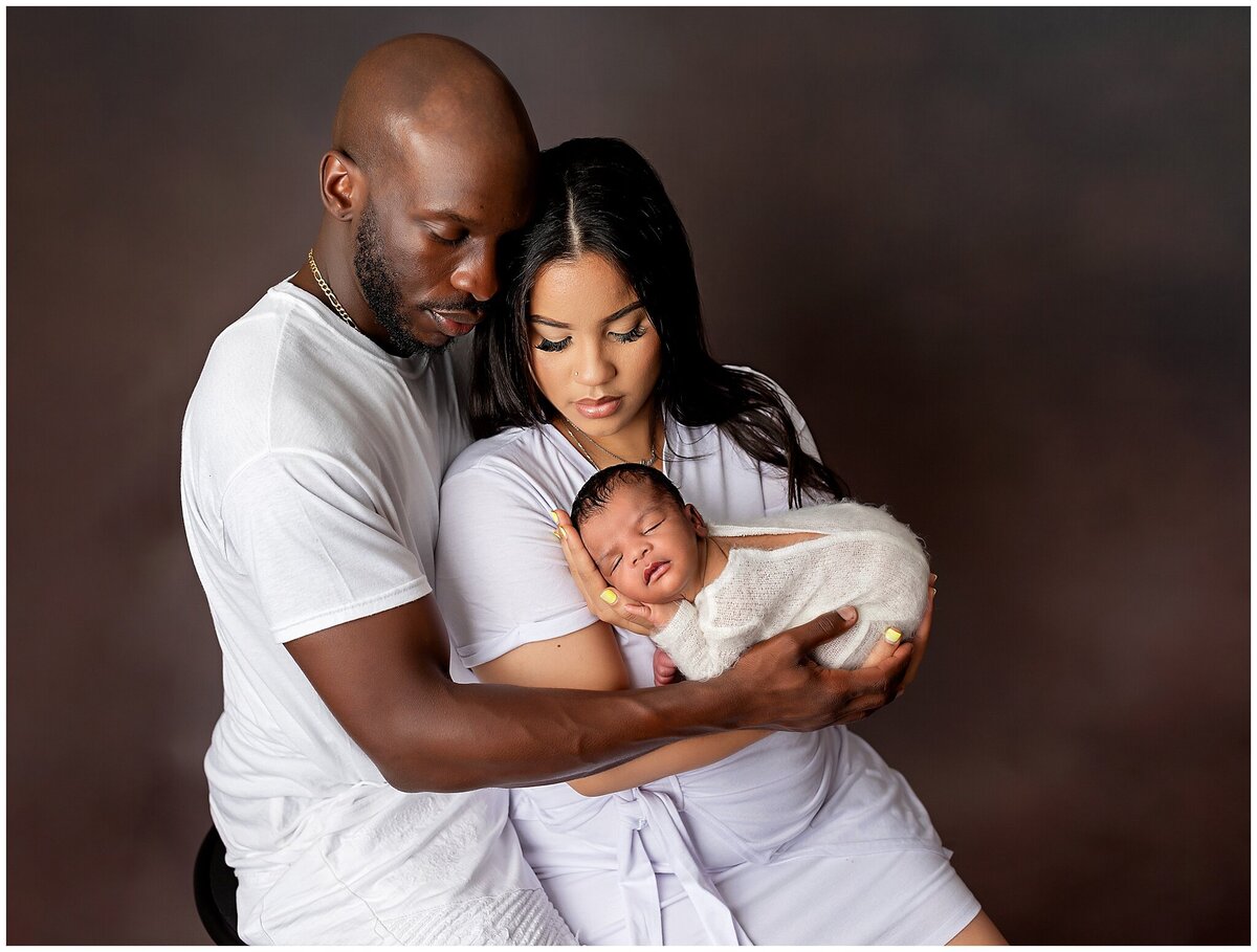 A precious moment captured: A newborn baby sleeping peacefully in their parents arms during a family photography session.