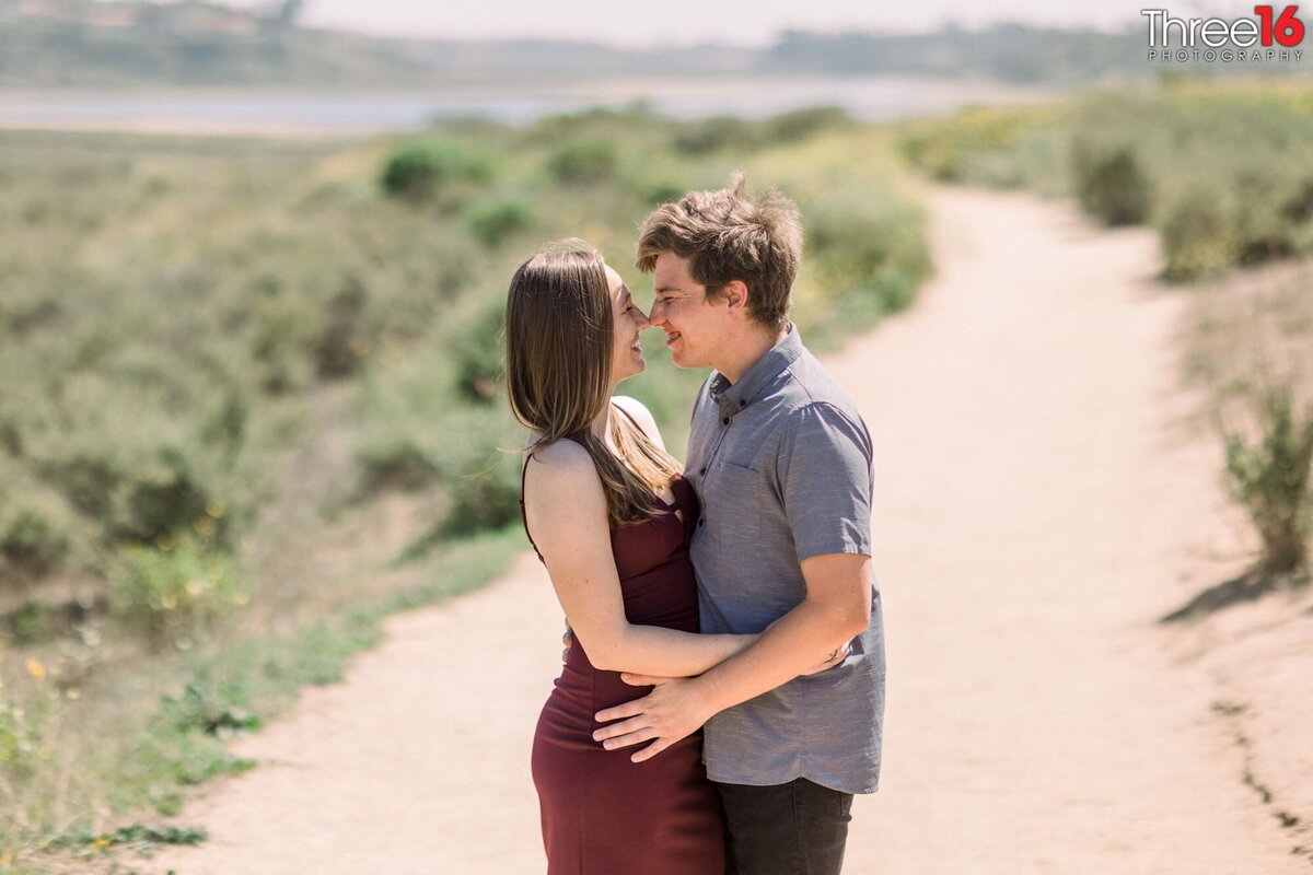 Engaged couple gaze into each other's eyes as they embrace each other during photo session