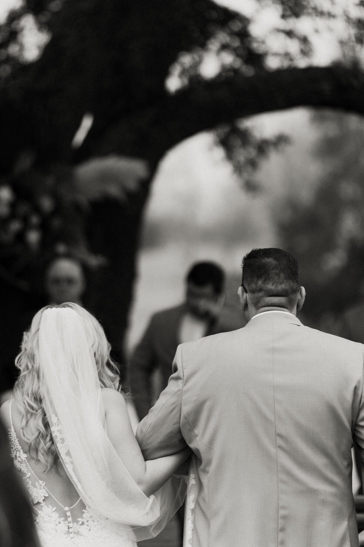 black and white image bride walks down aisle