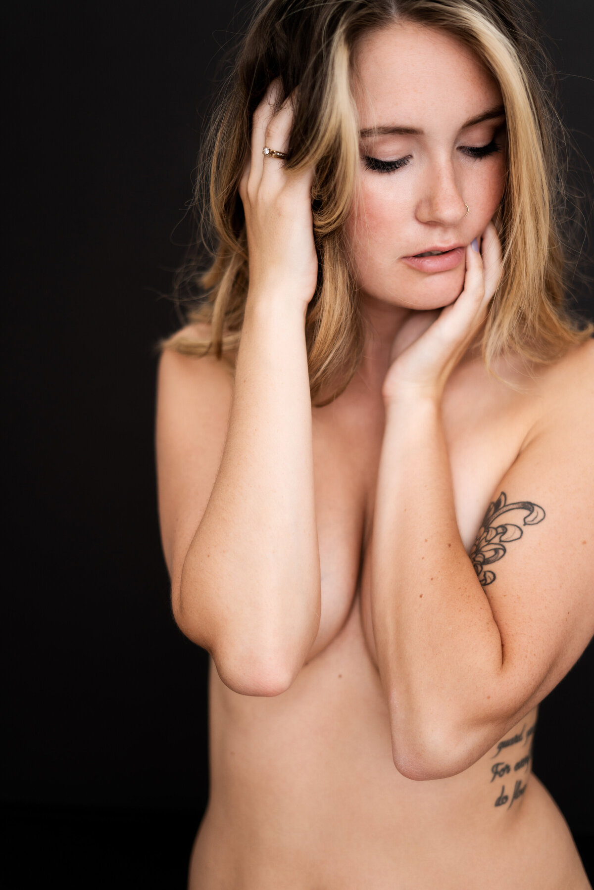 implied nude woman with tattoos hands on face and in hair