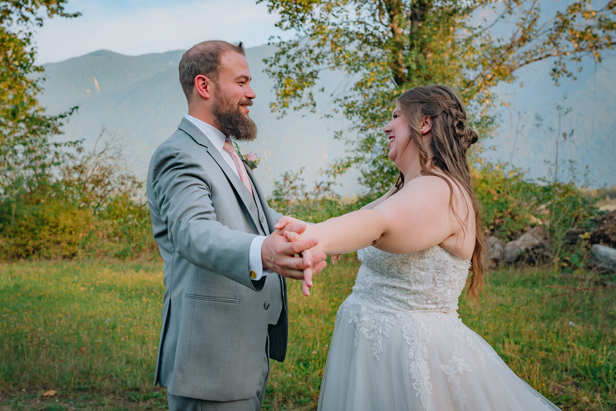 wedding-couple-smiling-at-each-other-holding-hands-outward