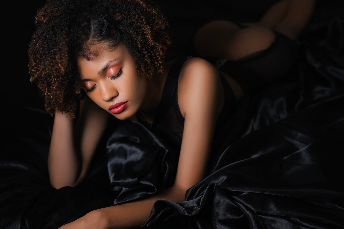 boudoir-portrait-of-a-woman-of-color-on-black-satin-sheets