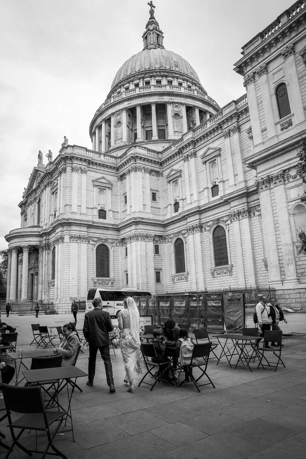 Bride and groom walking with coffee .  St Pauls in view