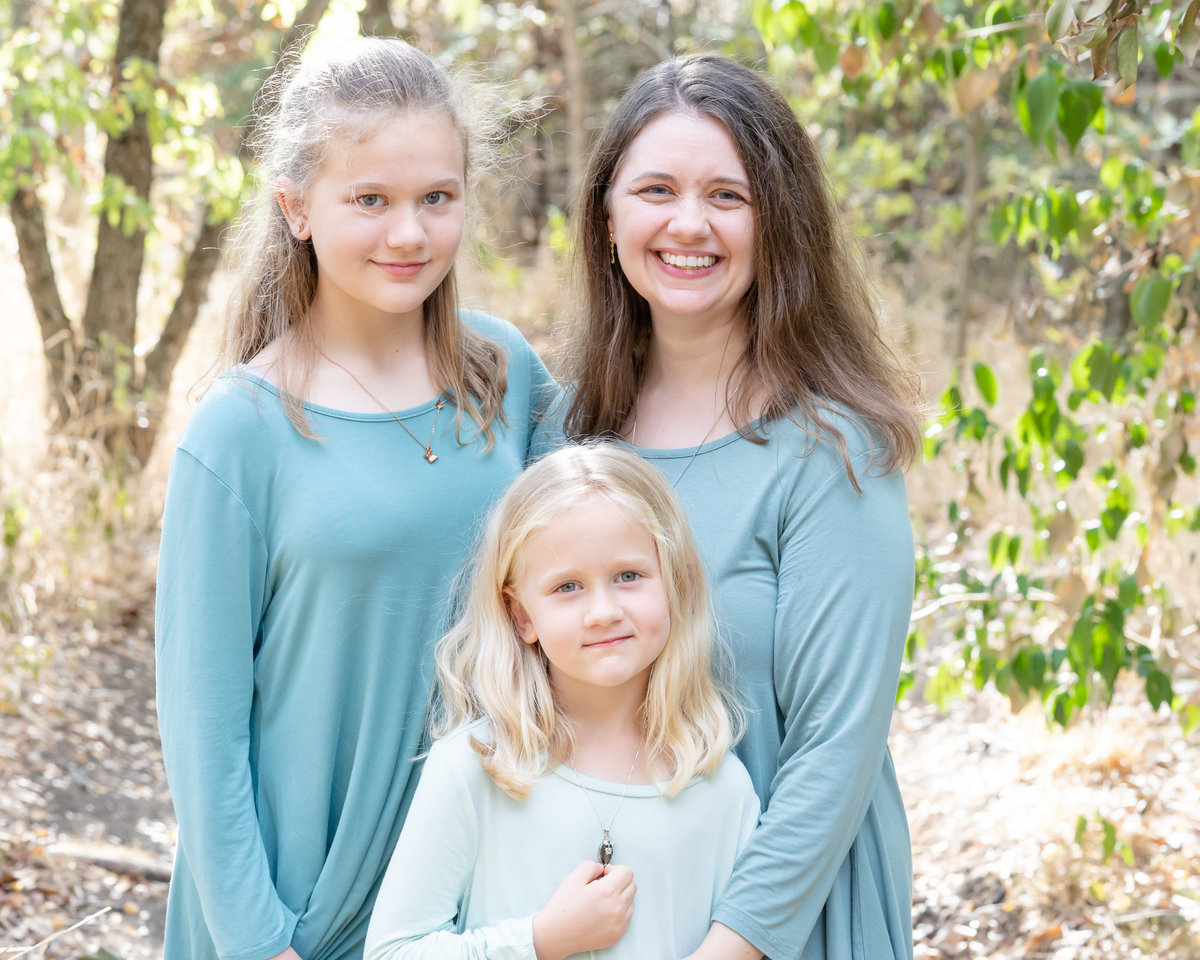 Mom and two daughters. Dressed in turquoise long sleeved shirts