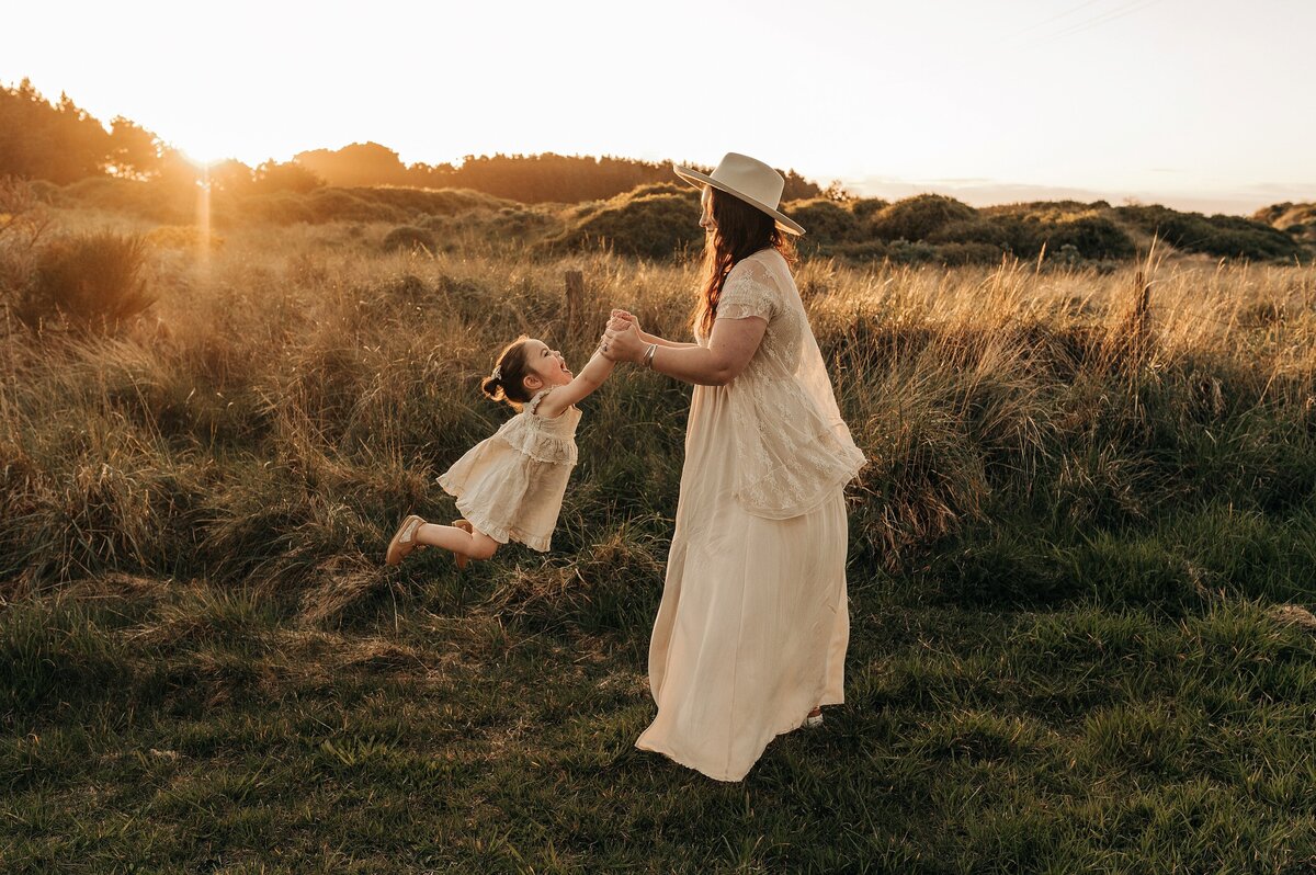 mother daughter swing dance together sunset neutral cream clothing hat dress golden light glow christchurch family