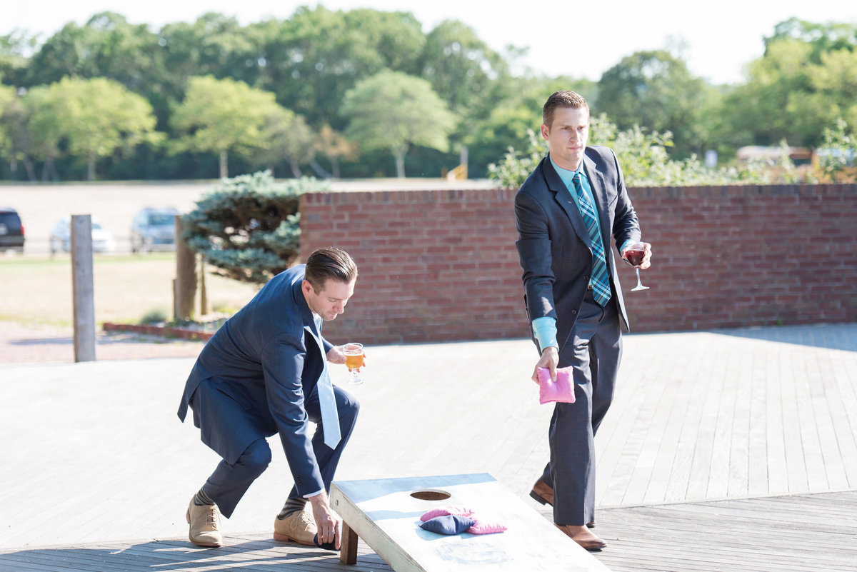 photo of groomsen playing bag toss during beach wedding reception at Pavilion at Sunken Meadow