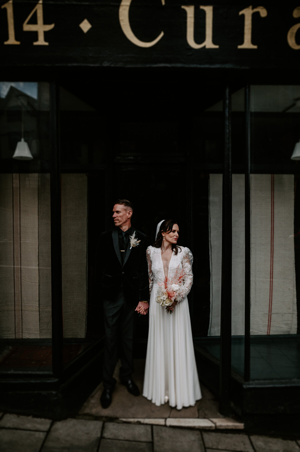 A wedding couple face away from each other in a wedding portrait in a black shop door way near The Mount Without in Bristol.